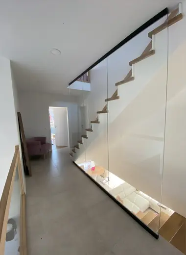 Moderne Treppe mit Glastrennwand und eleganten Geländer in einem hellen, minimalistisch gestalteten Wohnraum von AP Glas GmbH.