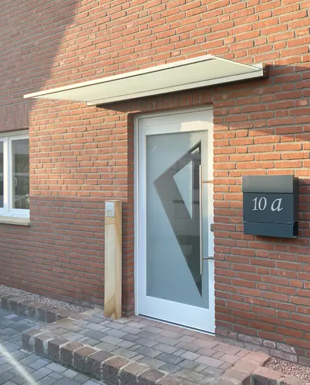 Moderne Eingangstür mit Glasvordach und stilvollem Design, installiert von AP Glas GmbH in Delbrück, spezialisiert auf Glaslösungen wie Brüstungen und Trennwände.
