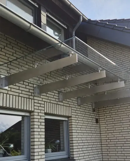 Glasvordach mit Edelstahlträgern an einem modernen Gebäude, ideal für stilvolle und funktionale Eingangsbereiche.