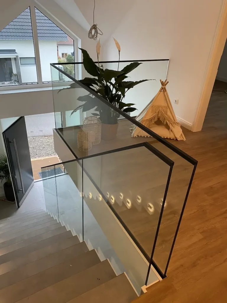 Moderne Glasbrüstung in einem stilvollen Innenraum, die Transparenz und Eleganz bietet, ideal für Treppenhäuser und offene Wohnkonzepte.